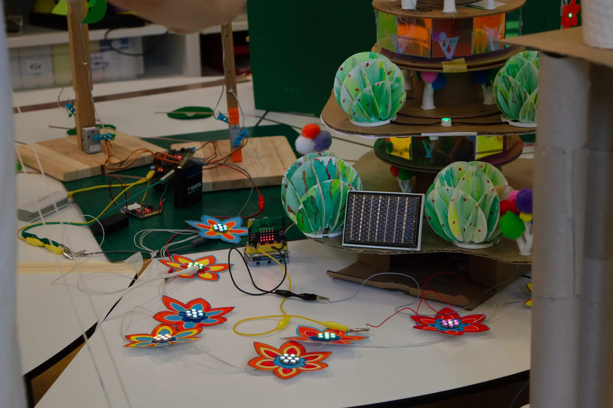 Leuchtende NeoPixel-Ringe in Papierblüten, verbunden mit einem micro:bit