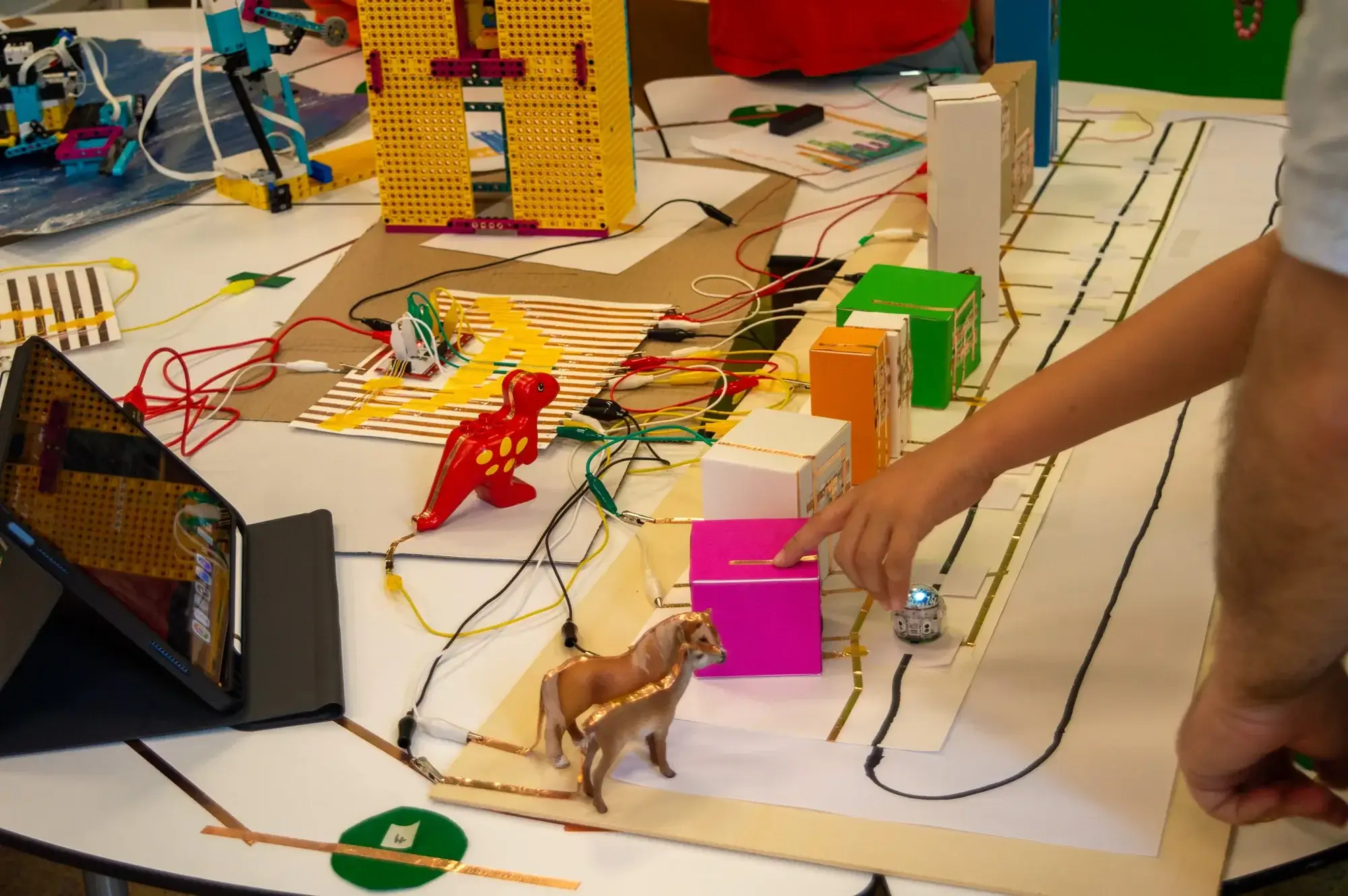 Kinderhände steuern einen Lego-Spike-Roboter über den Tisch